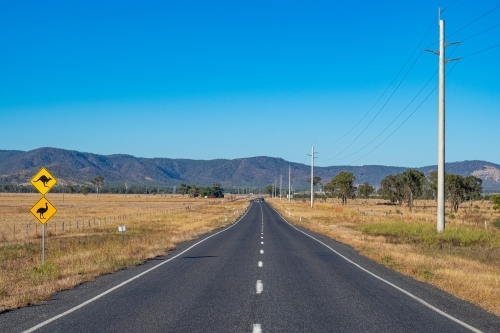 Close up photo of a road and bush land with yellow signages - Australian Stock Image