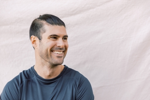 Close up photo of a smiling young men with stylish hair while looking at his right side - Australian Stock Image