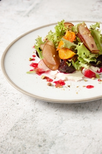 Close up - Plate of fresh salad of lettuce, beetroot, radish, stone fruit and vinaigrette