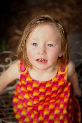 Close up portrait from above of little girl wearing red dress - Australian Stock Image