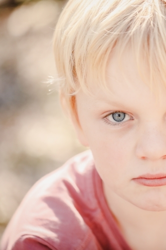 Close up portrait image of young boy with serious expression - Australian Stock Image