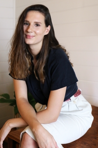 Close up portrait of a young female creative industry worker sitting on her desk - Australian Stock Image