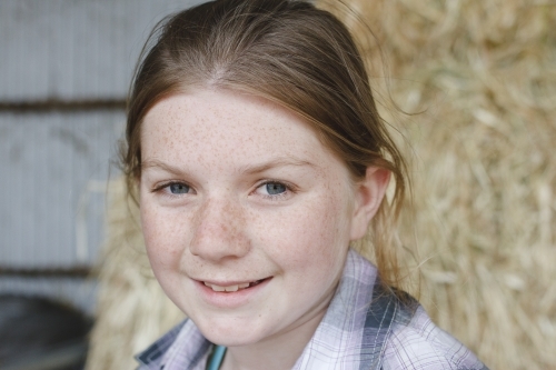 Close up portrait of a young girl in a hay shed - Australian Stock Image