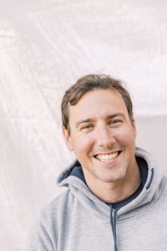 Close-up portrait of a young sports man smiling with a grey hoodie - Australian Stock Image