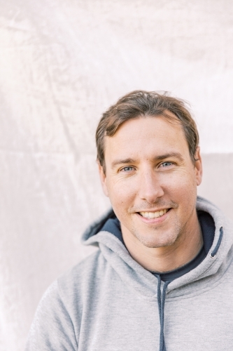 Close-up portrait of a young sportsman smiling wearing a grey hoodie - Australian Stock Image