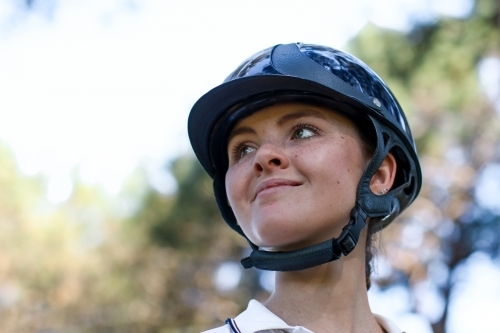 Close up portrait of happy young female horse rider wearing helmet