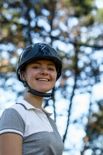 Close up portrait of happy young female horse rider wearing helmet - Australian Stock Image