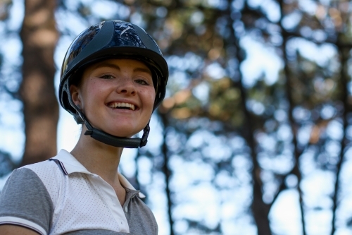Close up portrait of happy young female horse rider wearing helmet