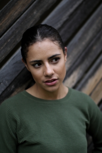 Close up portrait of young Fijian woman standing in front of textured wooden panels - Australian Stock Image