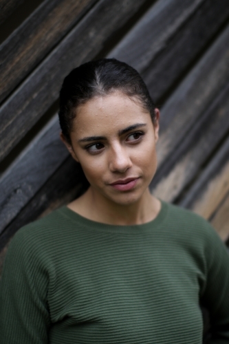 Close up portrait of young Fijian woman standing in front of textured wooden panels - Australian Stock Image