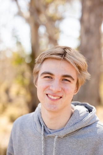 Close up portrait teen boy smiling wearing hoodie in bushland