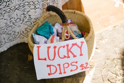 Close up shot of a basket with cloth inside and a signage that says lucky dips $2 - Australian Stock Image
