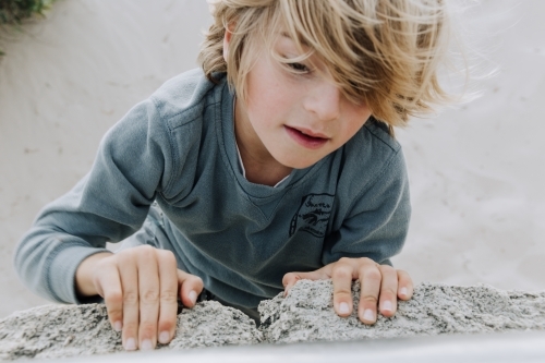 Close up shot of a boy climbing on a pile of rocks. - Australian Stock Image
