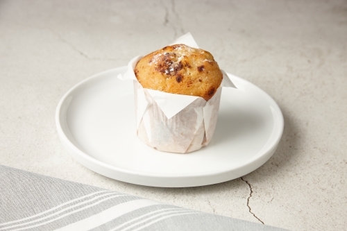 close up shot of a chocolate muffin on a white plate - Australian Stock Image