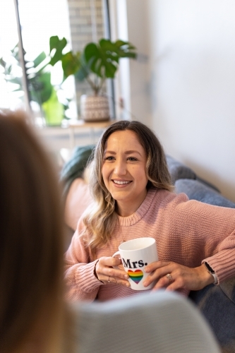 Close up shot of a smiling woman holding a white mug with pride symbol - Australian Stock Image