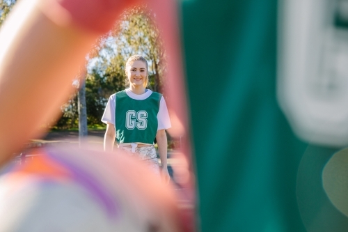 close up shot of a young woman framed in a blurry arm and net ball in the foreground - Australian Stock Image