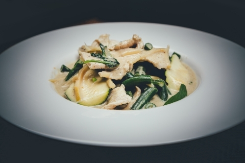 Close up shot of green curry chicken in a white plate - Australian Stock Image