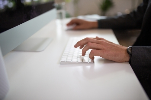 Close-up shot of man's hands typing on a keyboard - Australian Stock Image