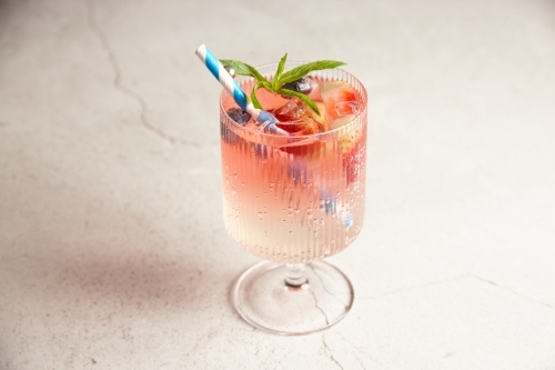 Close up shot of pink lemonade with white and blue striped straw and mixed berries - Australian Stock Image