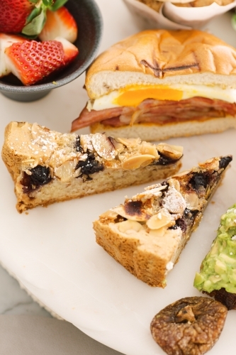Close up shot of slices of pies, half a sandwich and a bowl of strawberries. - Australian Stock Image