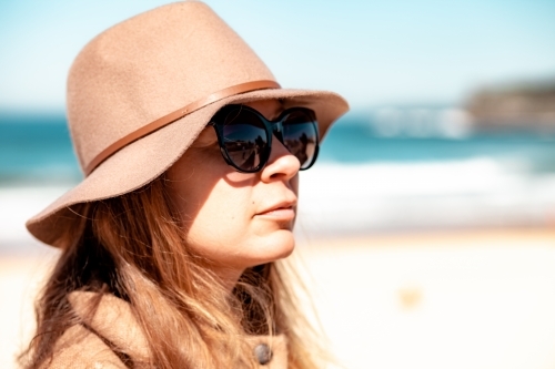 close up shot of woman in the beach wearing a hat and sunglasses - Australian Stock Image