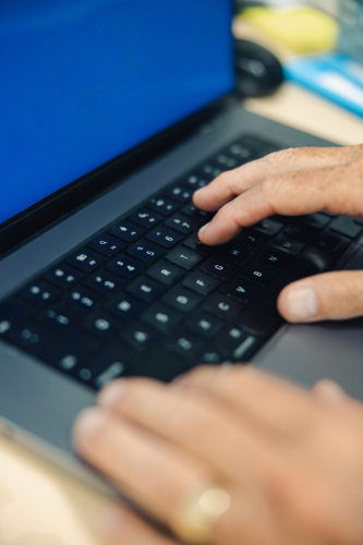 Close-up view of hands actively typing on a laptop keyboard - Australian Stock Image