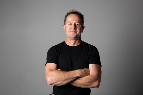 Close -up, waist high, portrait of a man with arms folded.