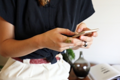 Closeup detail of a young creative female worker at her office desk using smart phone - Australian Stock Image