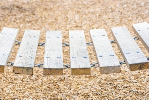 Closeup of a wooden chain bridge in playground sunny day - Australian Stock Image