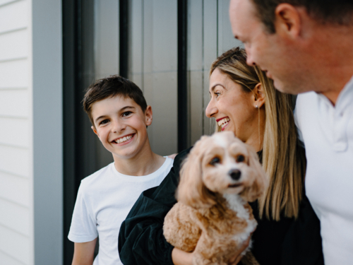 Closeup of a young boy smiling while parents look at him. - Australian Stock Image
