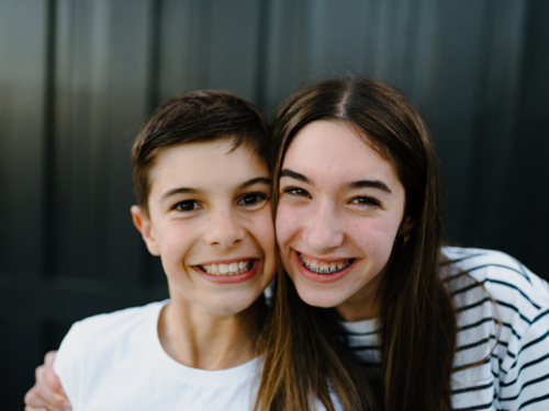 Closeup of brother and sister smiling at the camera. - Australian Stock Image