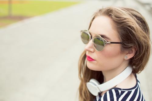 Closeup of young woman with headphones and sunglasses