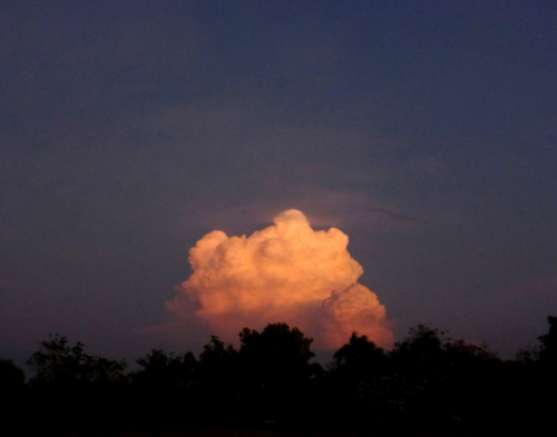 Cloud formation illuminated in golden orange against the night sky - Australian Stock Image