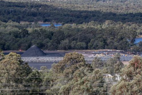 Coal mine tailings and stockpiles forming large mounds across an industrial landscape - Australian Stock Image