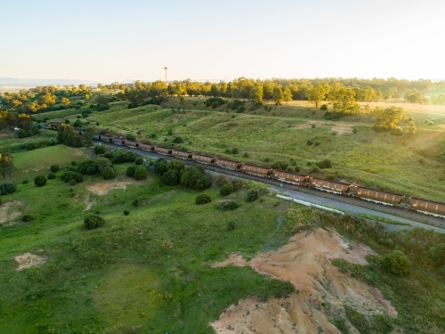 Coal train seen from drone on railway track through green landscape in Hunter Valley - Australian Stock Image