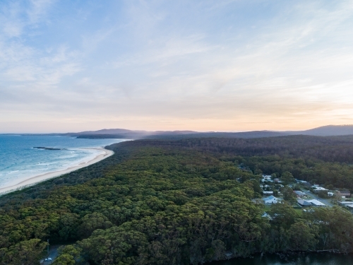 Coastal scene at dusk forest running down to empty sandy beach - Australian Stock Image