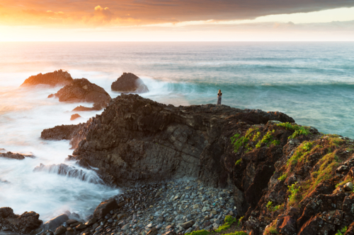 coastal sunrise scene on rugged, rocky coastline with crashing ocean waves - Australian Stock Image
