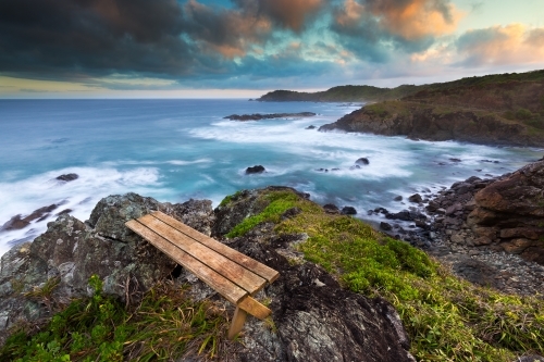 Coastline view from headland with a wooden bench on a stormy day