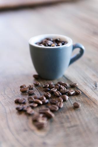 Coffee beans and cup with wood grain table background
