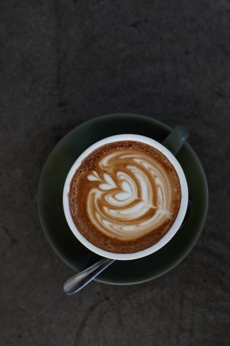 Coffee with froth decoration served on table - Australian Stock Image