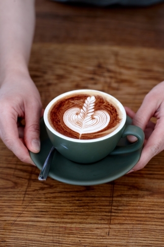 Coffee with froth decoration served on table - Australian Stock Image