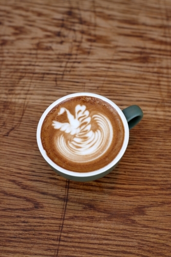 Coffee with froth decoration served on table - Australian Stock Image