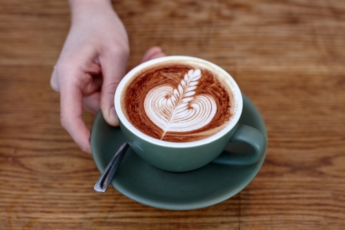 Coffee with froth decoration served on table - Australian Stock Image