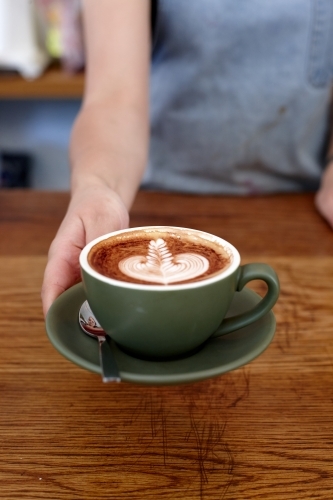 Coffee with froth decoration served on table - Australian Stock Image