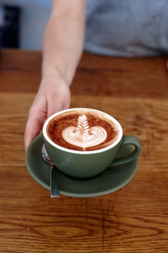 Coffee with froth decoration served on table - Australian Stock Image