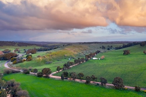 Colored cloud formations over country roads and green rural countryside - Australian Stock Image