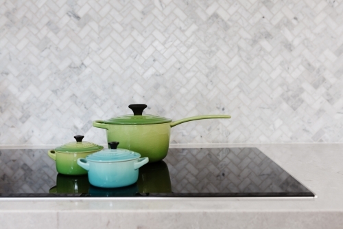 Colorful pots on display on a stove top - Australian Stock Image