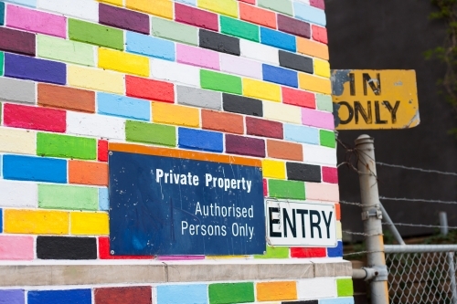 Coloured brick wall, signage and a gate on a city street