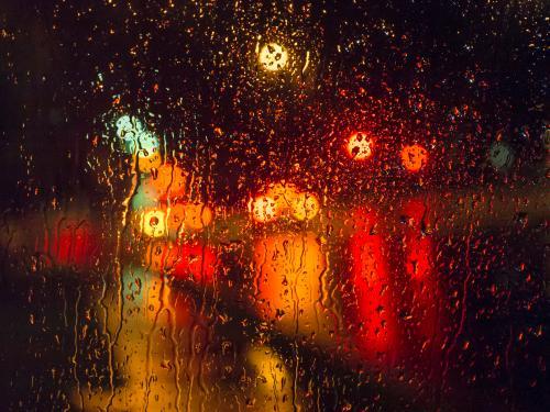Colourful city light patterns distorted by rain on a car windscreen - Australian Stock Image
