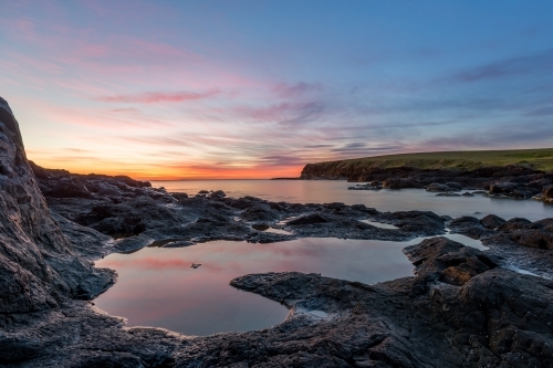 Colourful sunrise reflecting in ocean rock pools